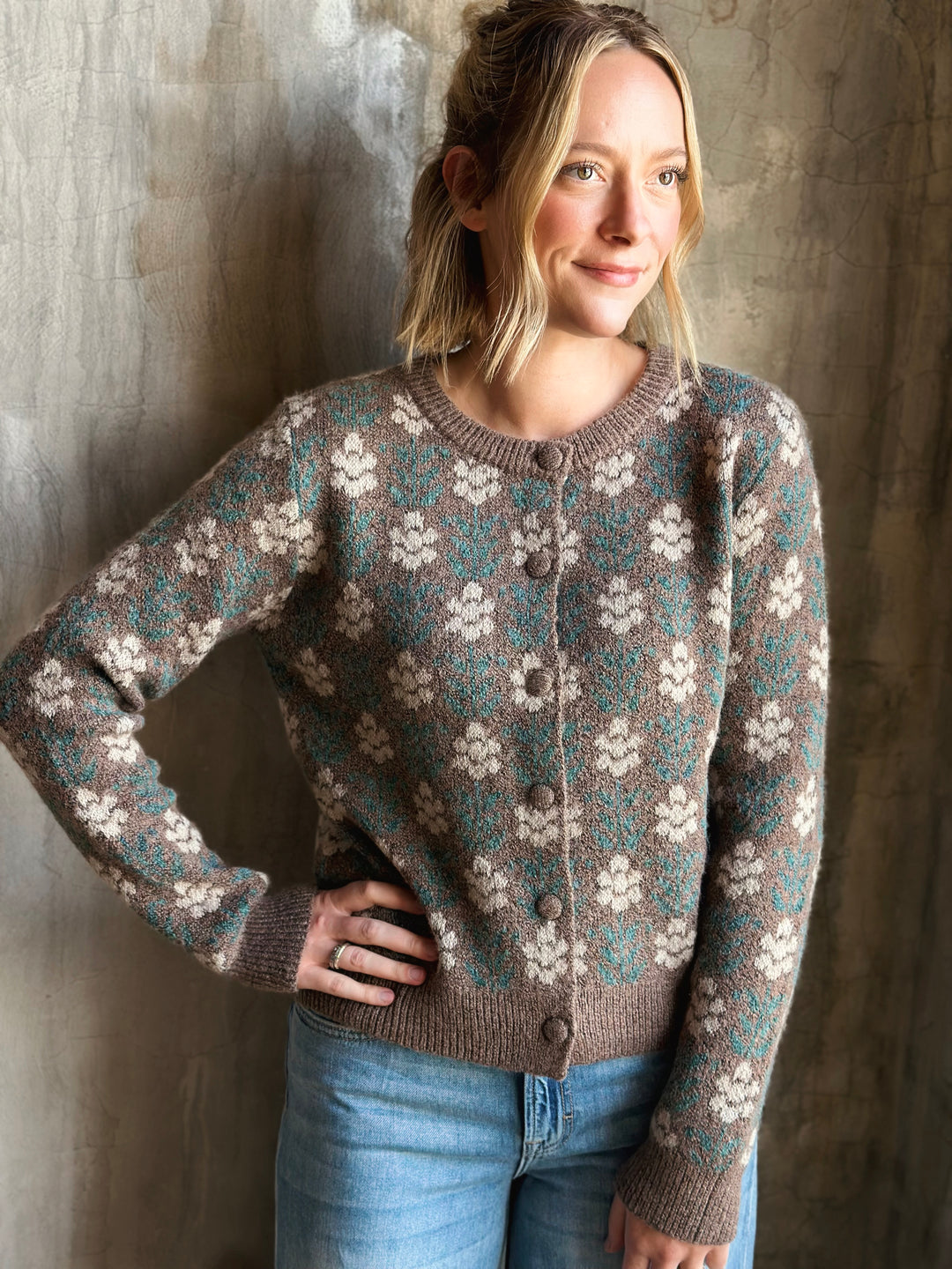 Woman wearing a patterned sweater against a textured wall