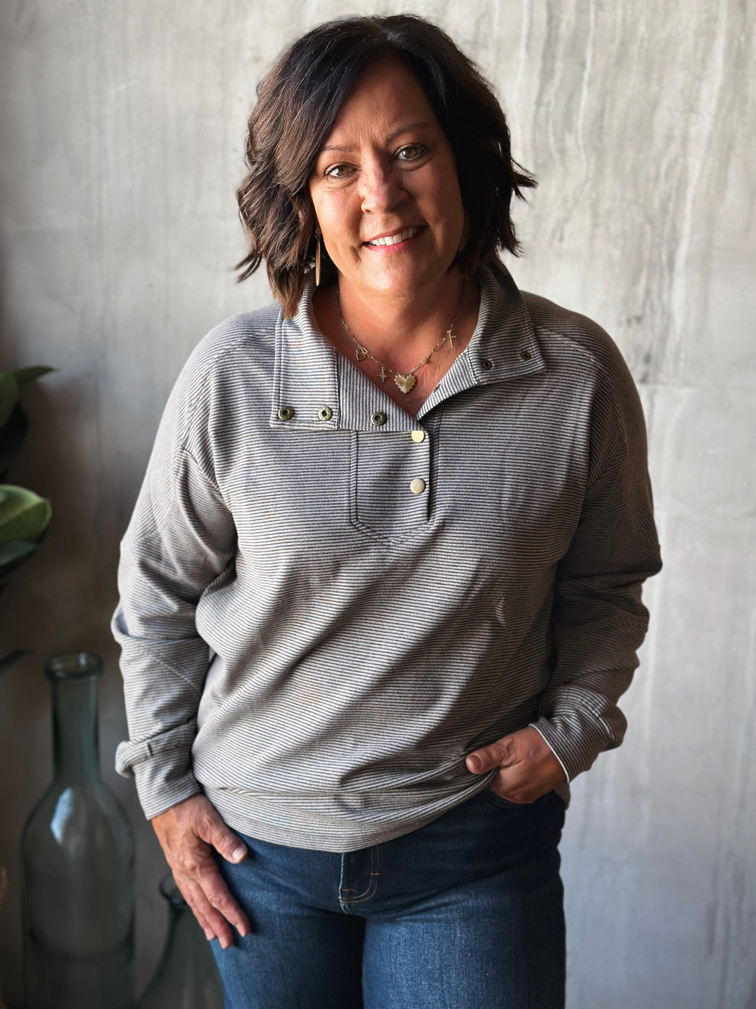 Woman wearing a gray pullover with a neutral background