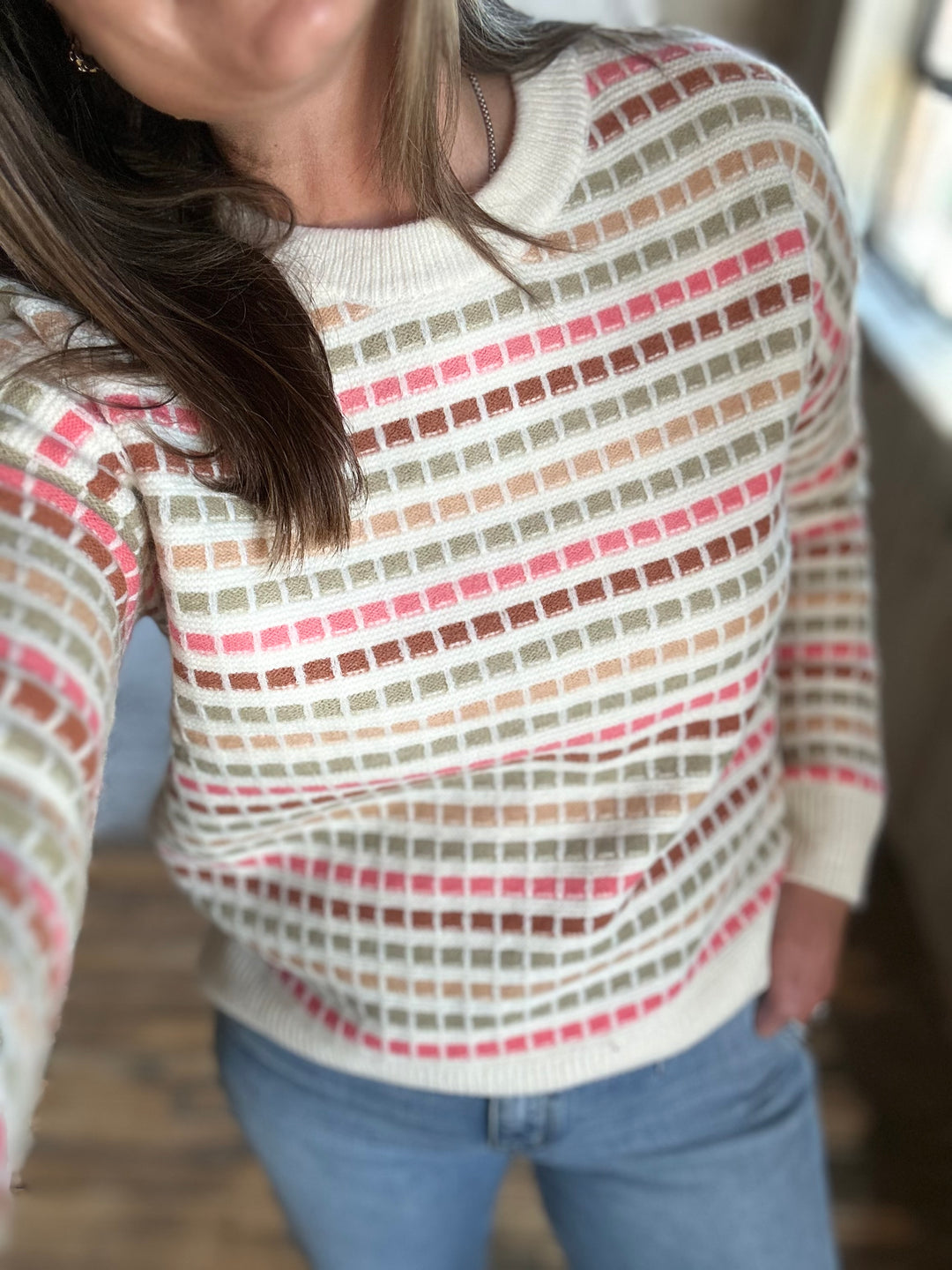 Close-up of the textured pink, green and red stripes on a cream sweater