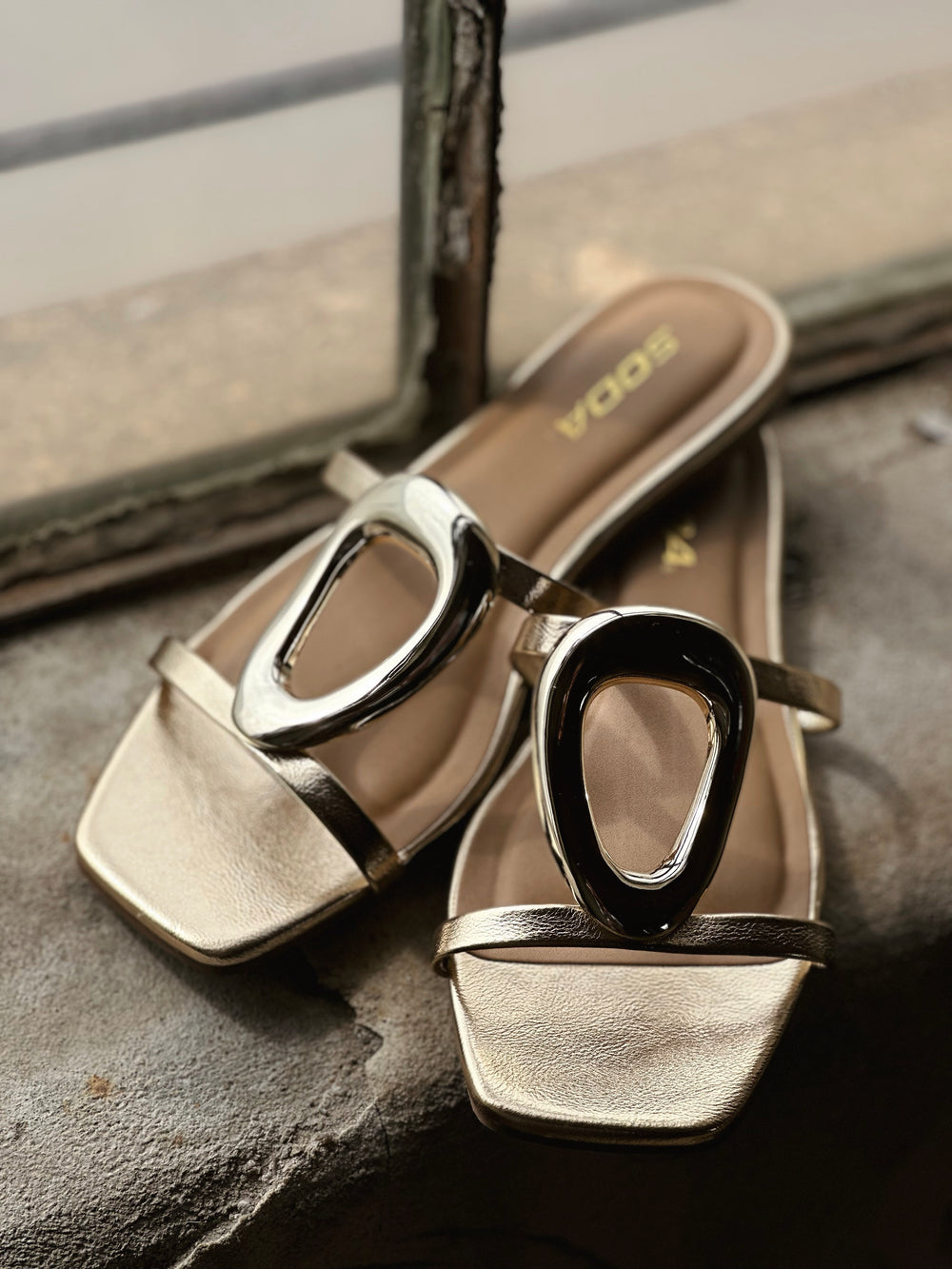 gold slip-in sandals. Featuring a sleek, minimalist silhouette and irregular oval detailing across the top, 