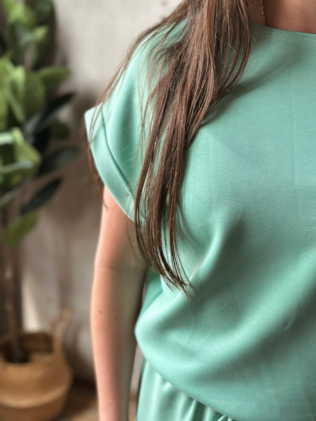 Person wearing a light green dress with a blurred background