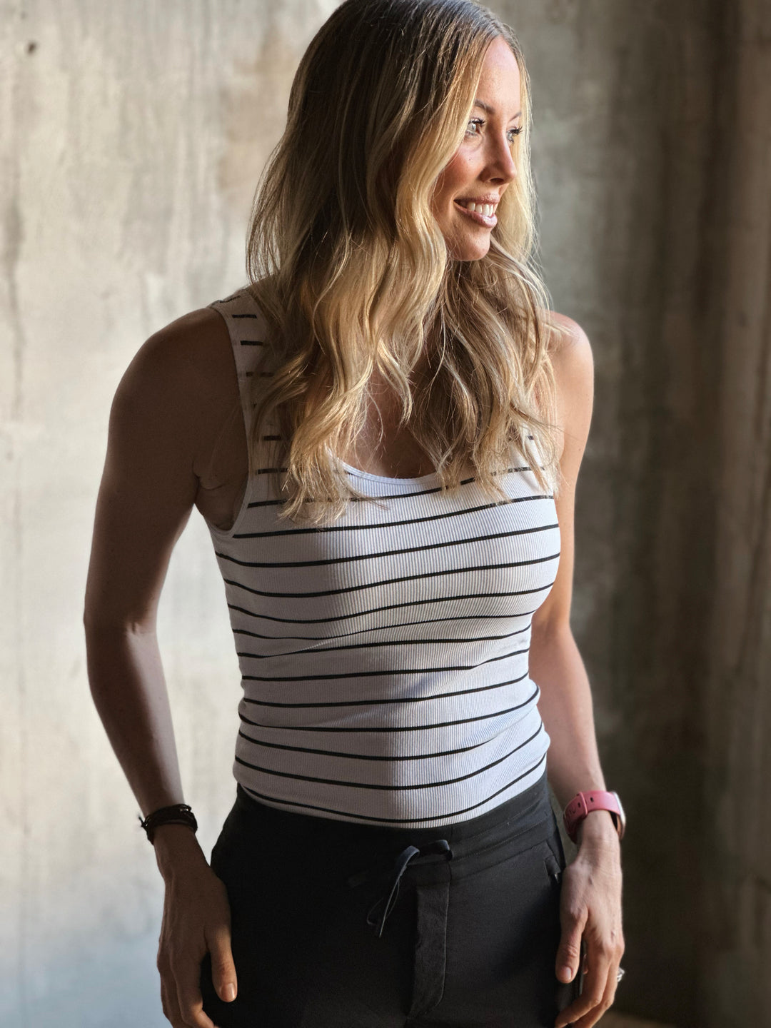 Woman wearing a striped tank top against a neutral background