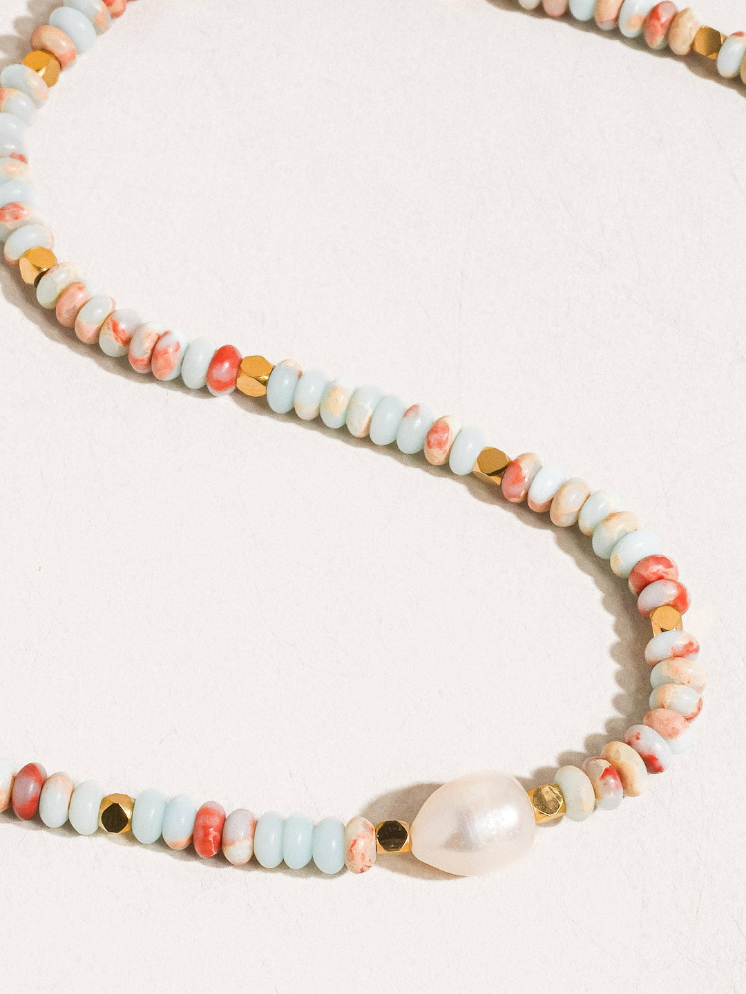 Necklace with multicolored beads and a pearl on a white background