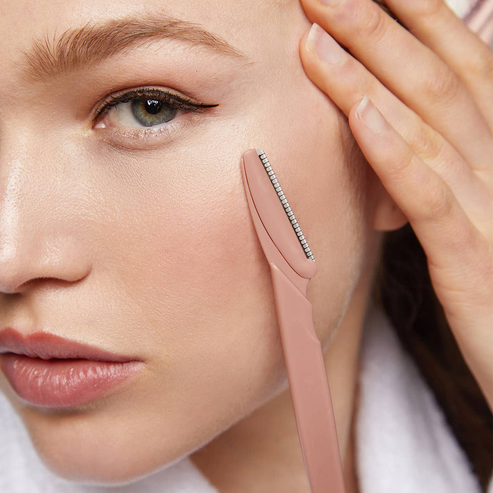 Woman using a pink skincare tool on her face