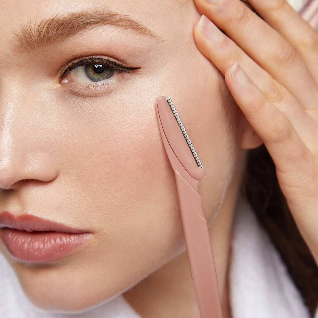 Woman using a pink skincare tool on her face