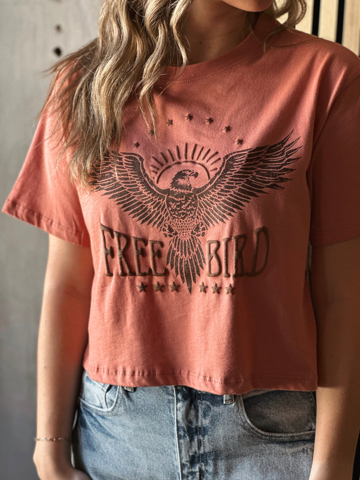 Front view of model wearing a mauve shirt with Free Bird graphic tee with puff print design