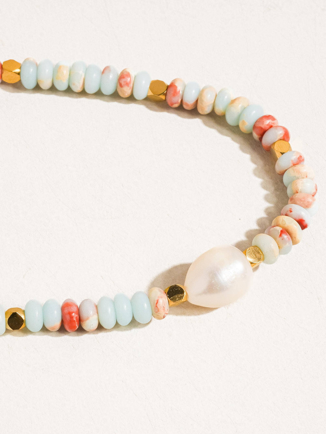 Multicolored beaded bracelet with a pearl on a white background