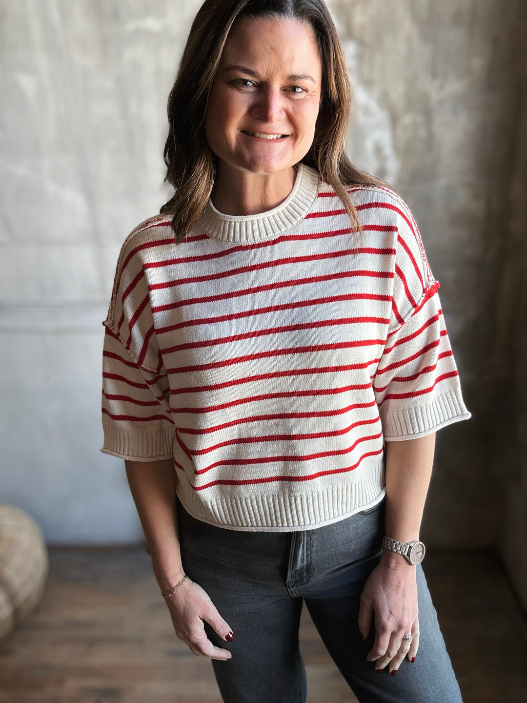 Woman wearing a white sweater with red stripes against a neutral background