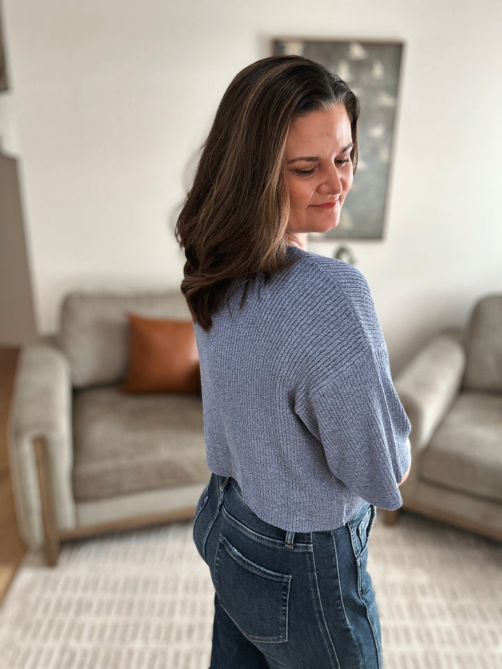 Woman wearing a blue sweater and jeans in a living room setting