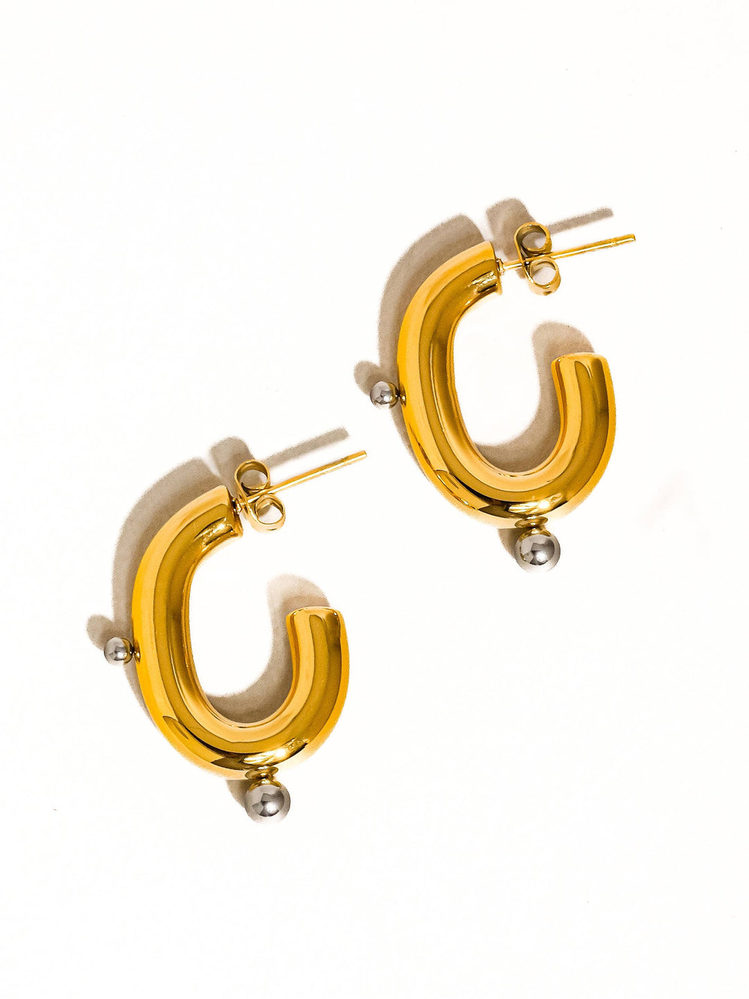 Gold hoop earrings with beige accents on a white background