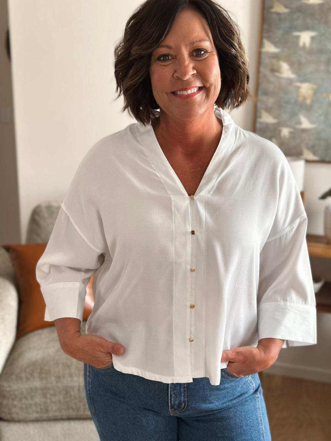 Woman wearing a white blouse and blue jeans in a living room setting