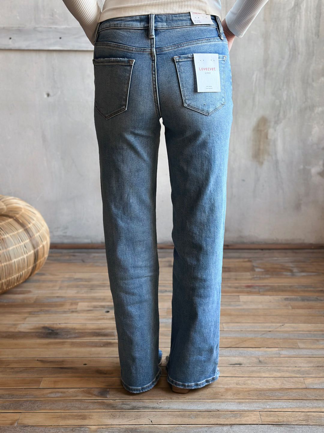 Person wearing blue jeans, standing on a wooden floor.
