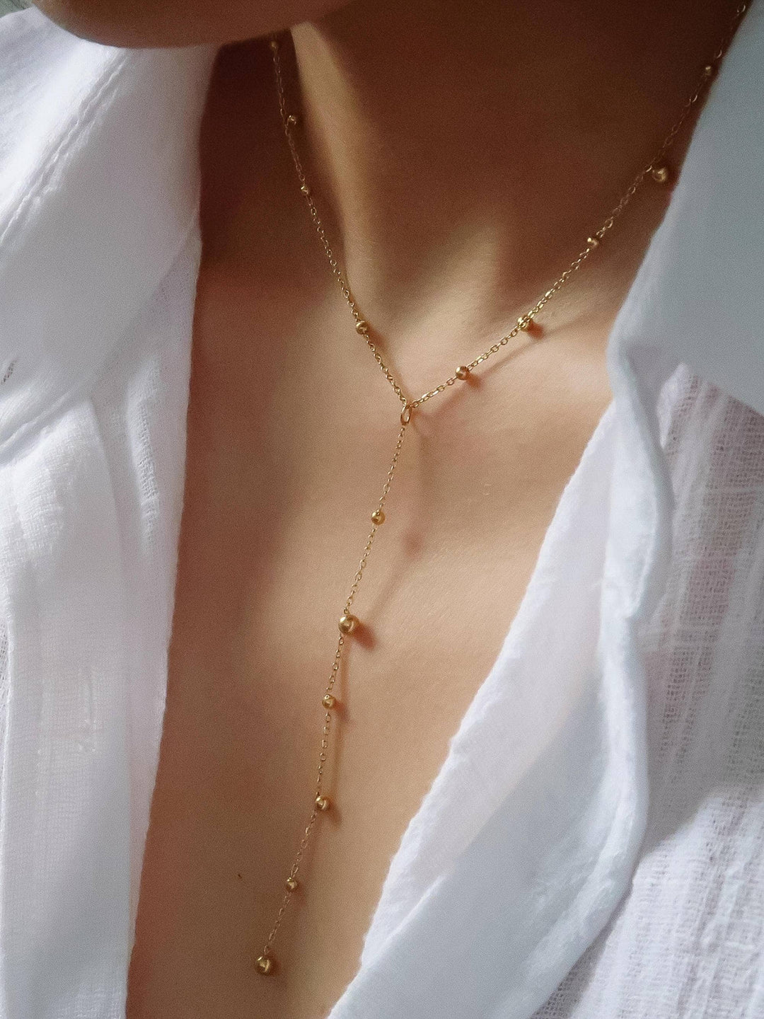 Gold necklace worn by a person with a white shirt