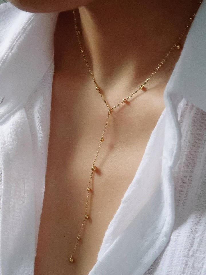 Gold necklace worn by a person with a white shirt