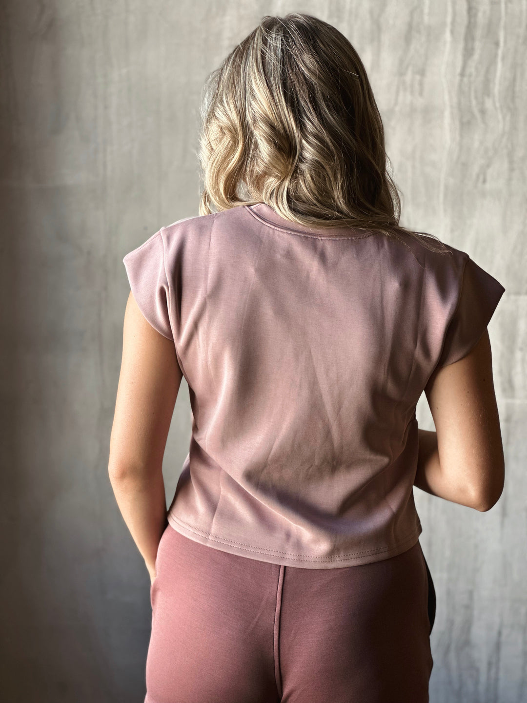 Person wearing a pink top and pants against a neutral background