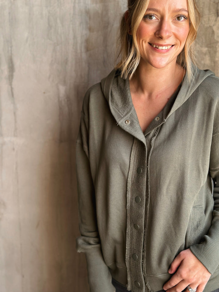 Woman wearing a green hoodie against a textured wall