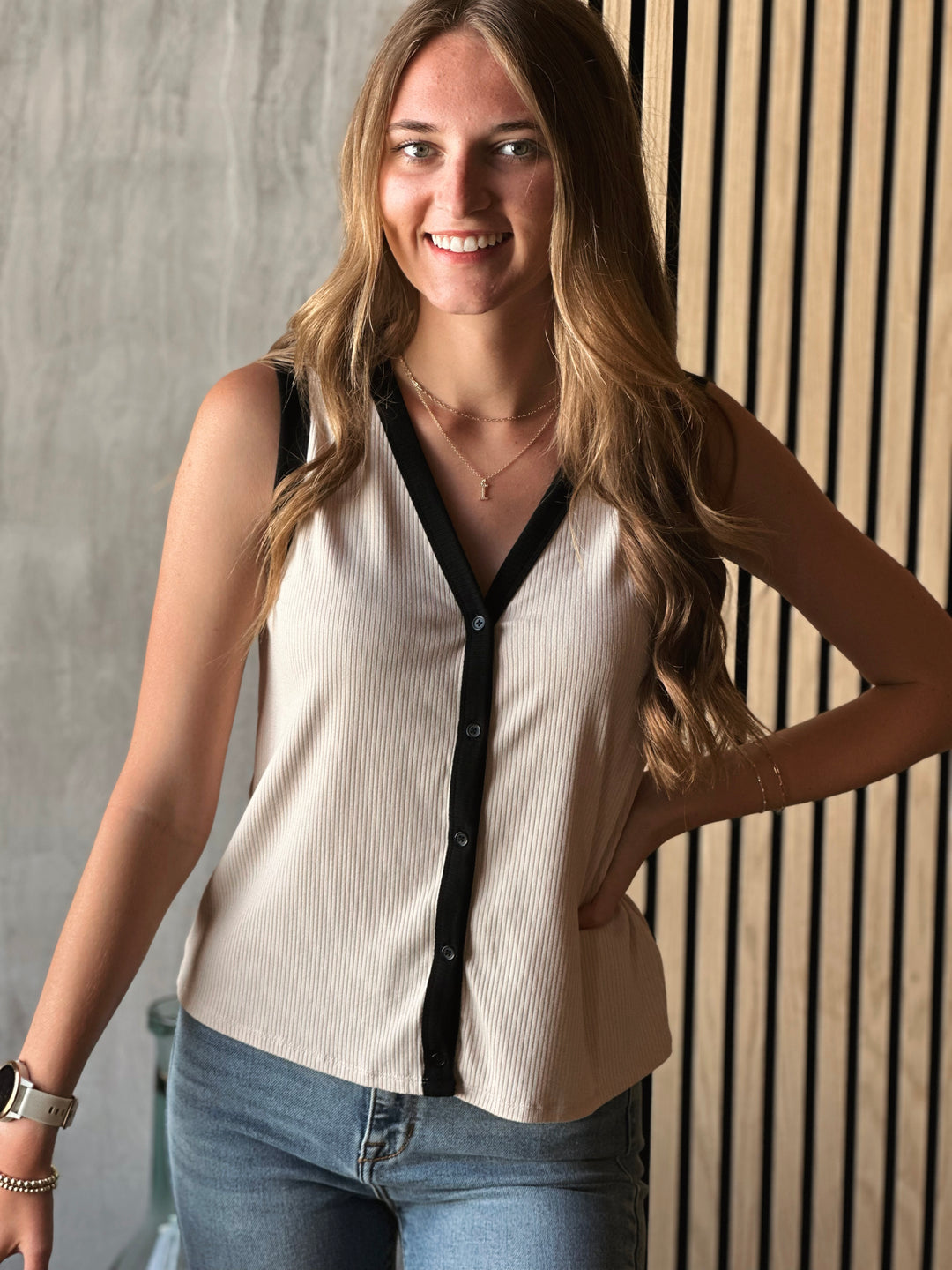 Front view of what model wearing sleeveless V-neck top with functional front button down and ribbed knit fabric