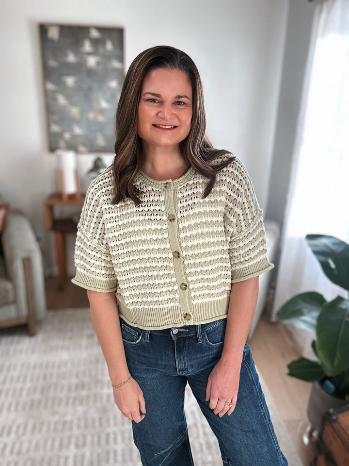 Woman wearing a textured light green cardigan in a home setting