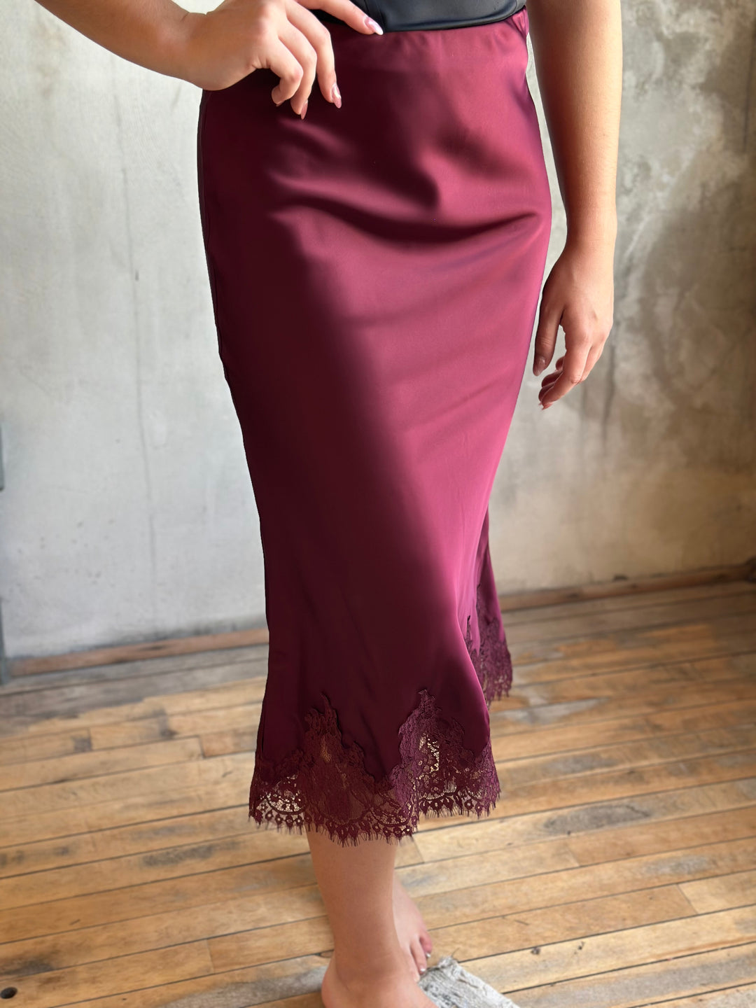 Burgundy satin midi skirt with a lace-trimmed hem, side view