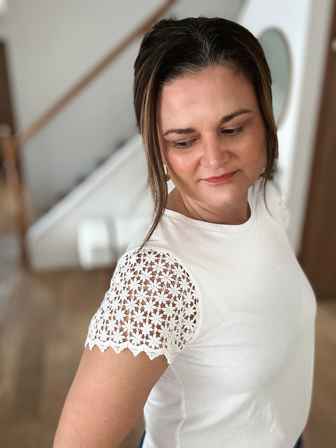 Woman wearing a white blouse with lace sleeves in an indoor setting