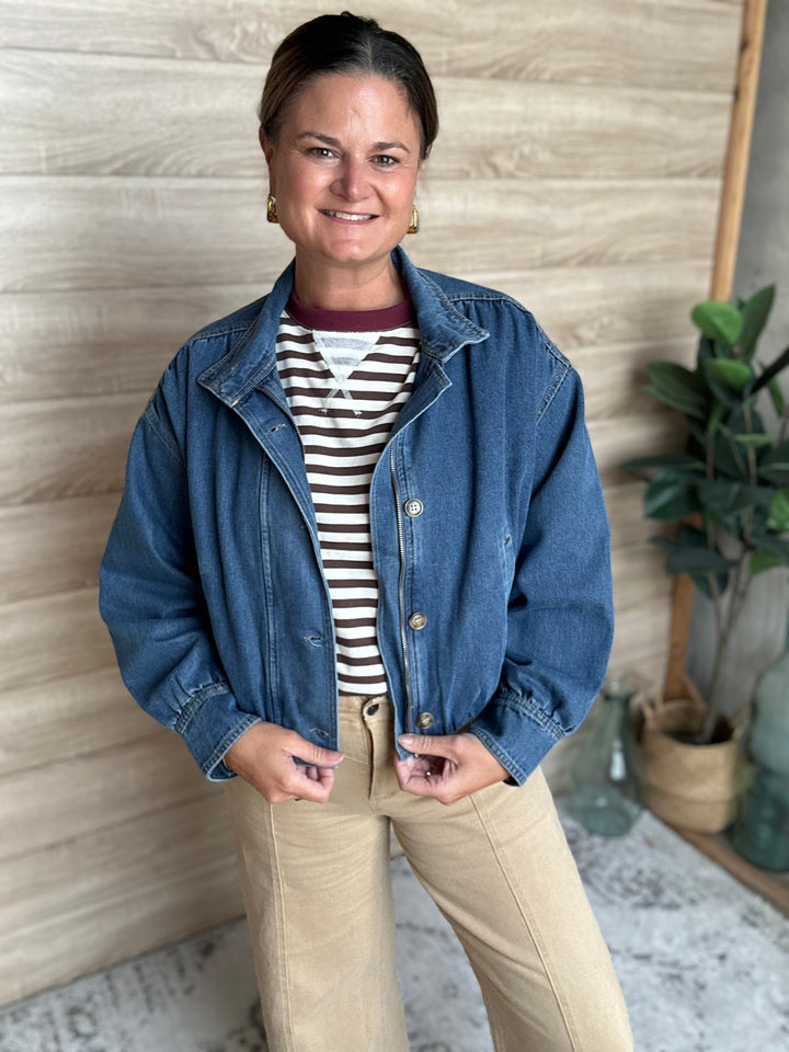 A woman wearing a puffy blue denim jacket with buttons down the middle.