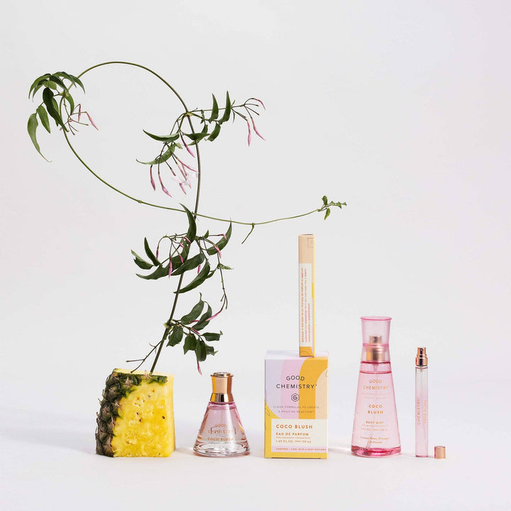 Collection of perfume bottles and a pineapple with a plant on a white background