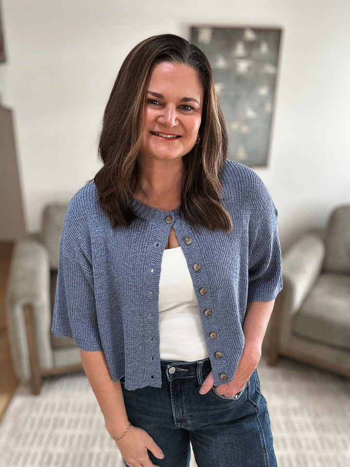 Woman wearing a blue cardigan in a living room setting