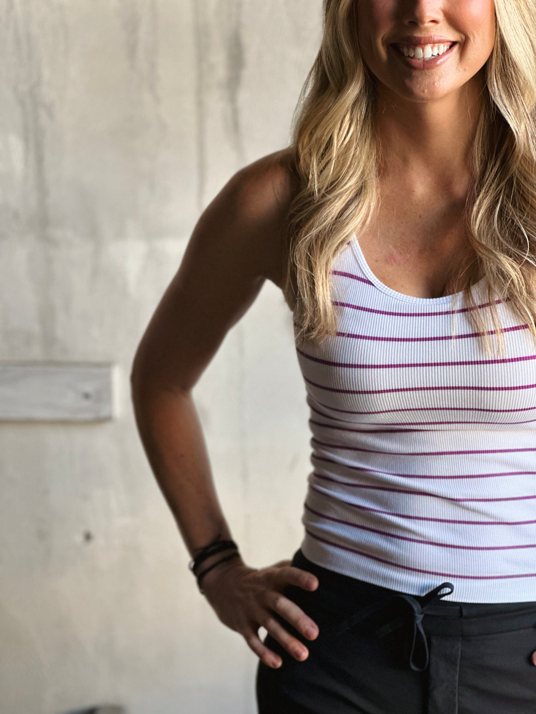 Woman wearing a white tank top with red stripes against a neutral background