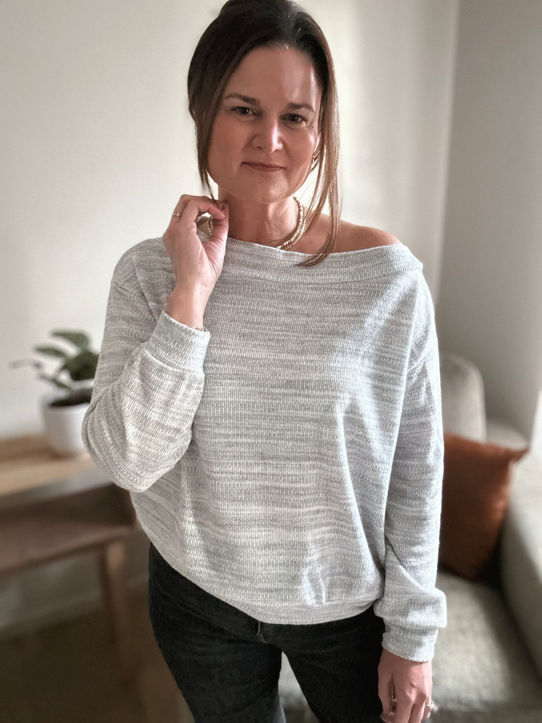 Woman wearing a gray sweater in a casual indoor setting