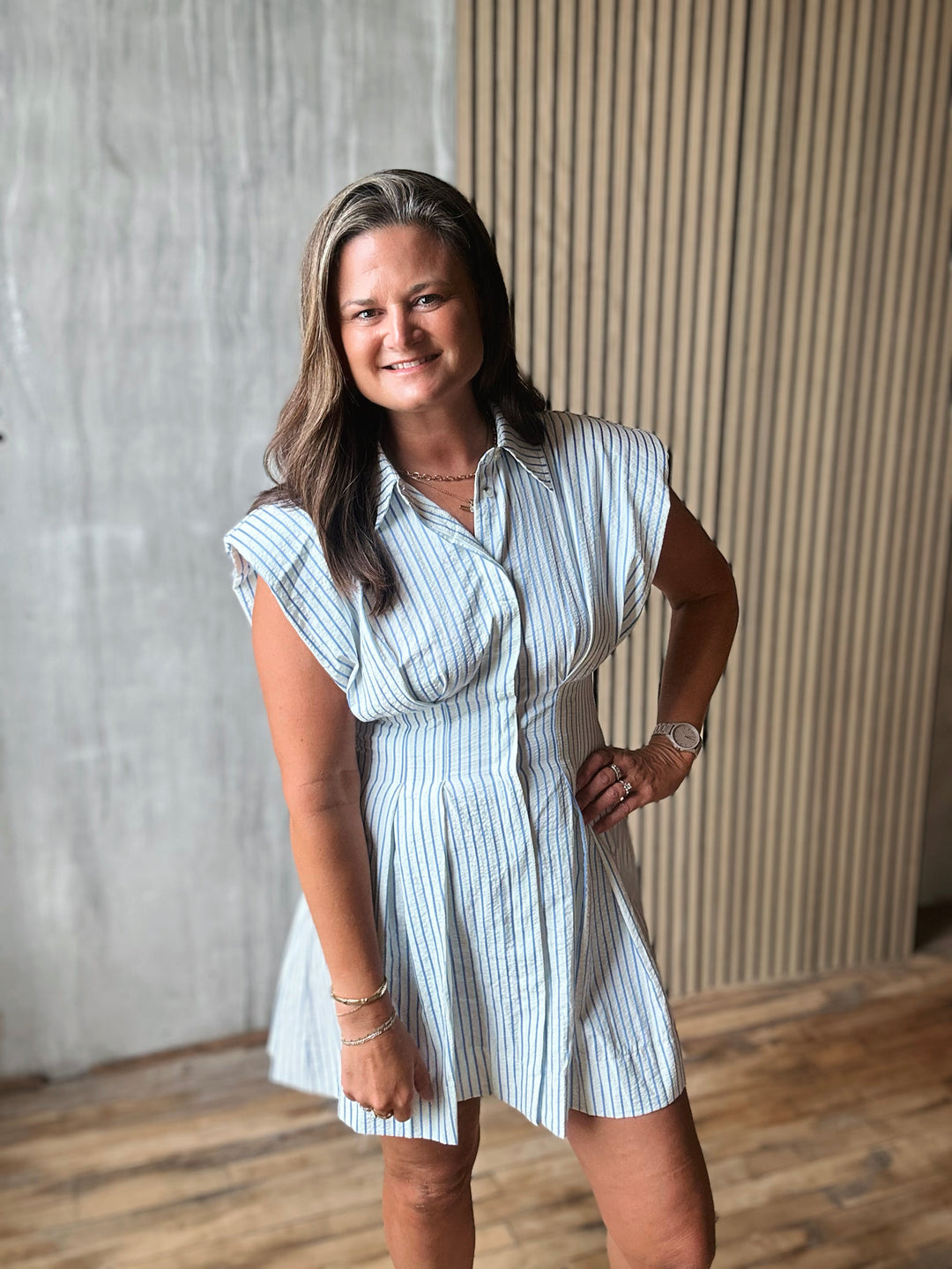 Woman wearing a white and blue striped dress standing against a neutral background