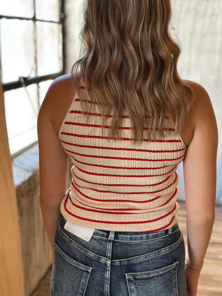 Person wearing a striped tank top and jeans in an indoor setting