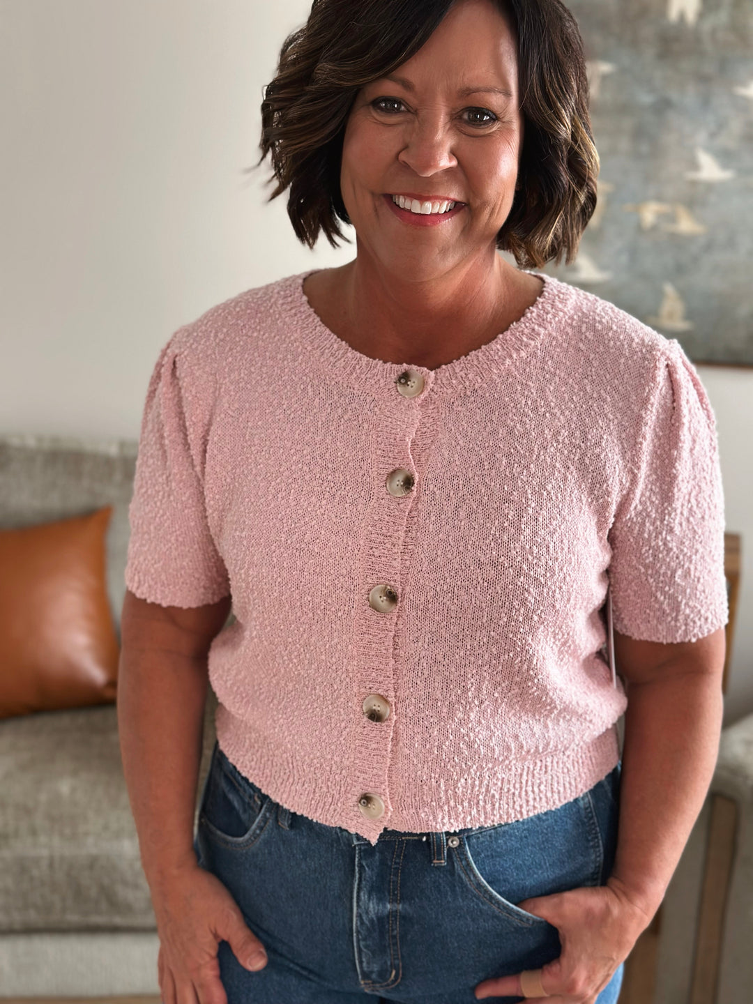 Woman wearing a pink textured cardigan with buttons facing forward 