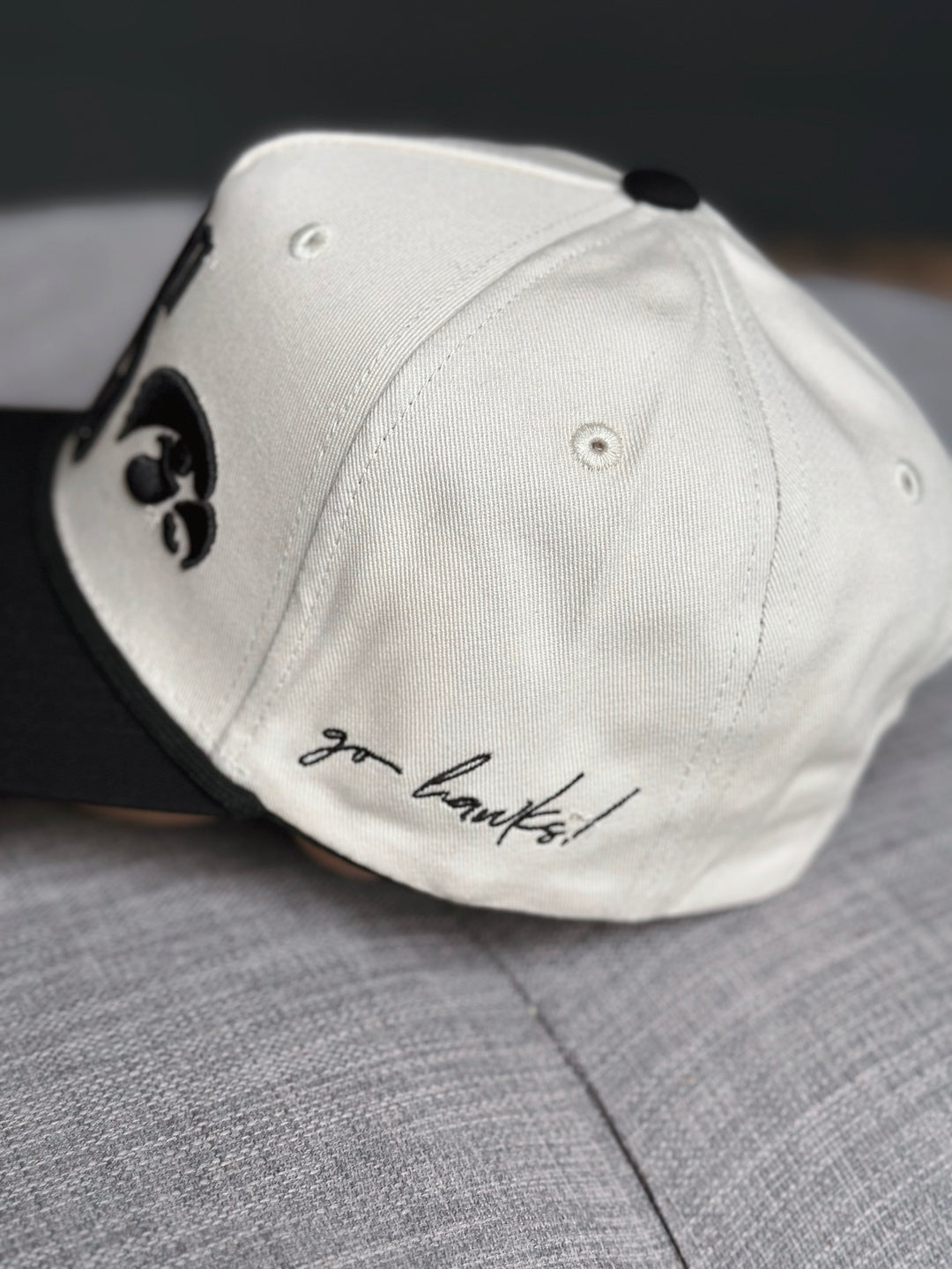 White cap with black logo and 'go hawks!' text on a gray surface