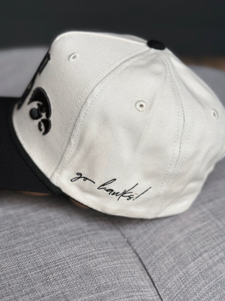 White cap with black logo and 'go hawks!' text on a gray surface