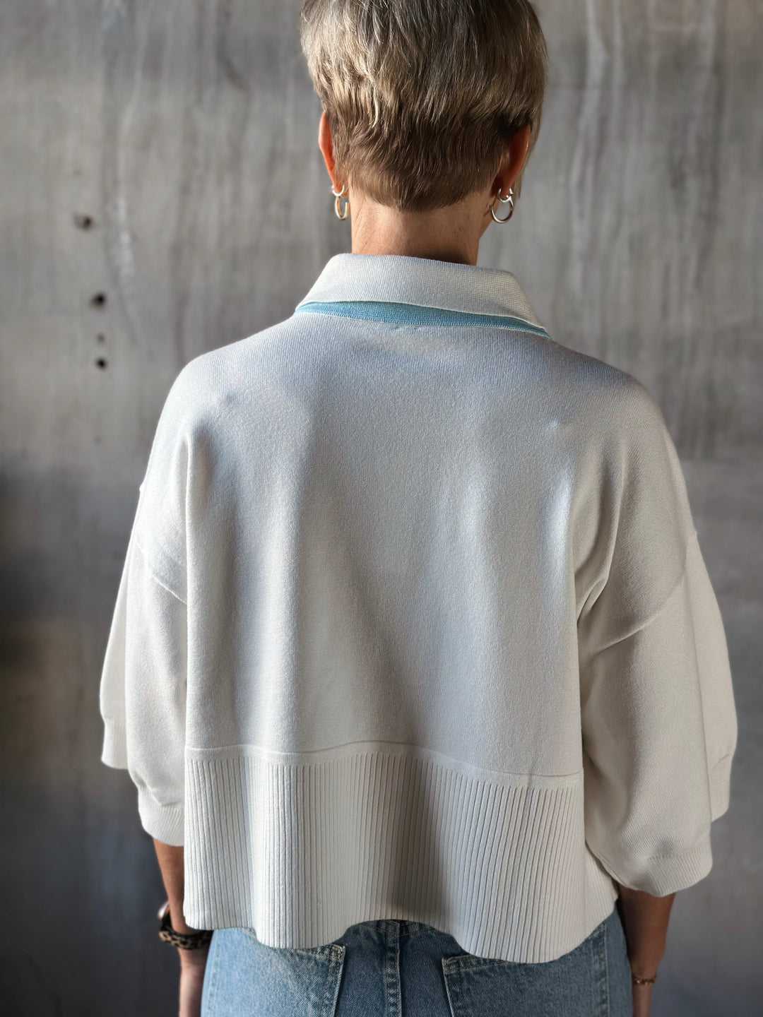 Person wearing a light-colored knit cardigan with a neutral background