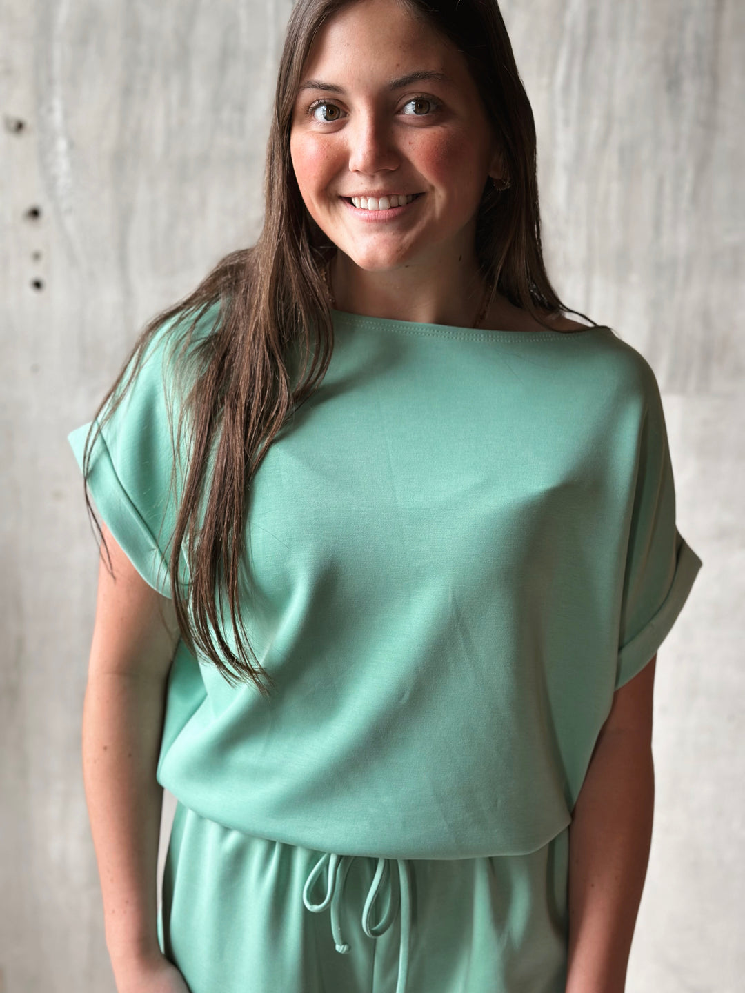 Woman wearing a light green top and shorts against a neutral background