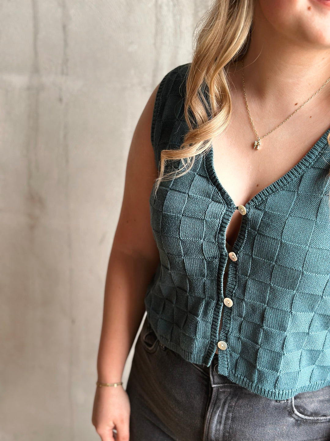 Person wearing a teal checkered vest with a neutral background