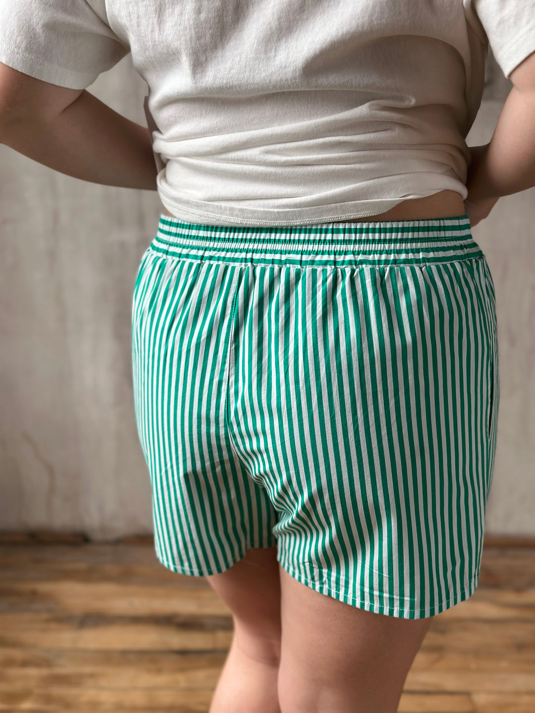 Person wearing green and white striped shorts with a plain background