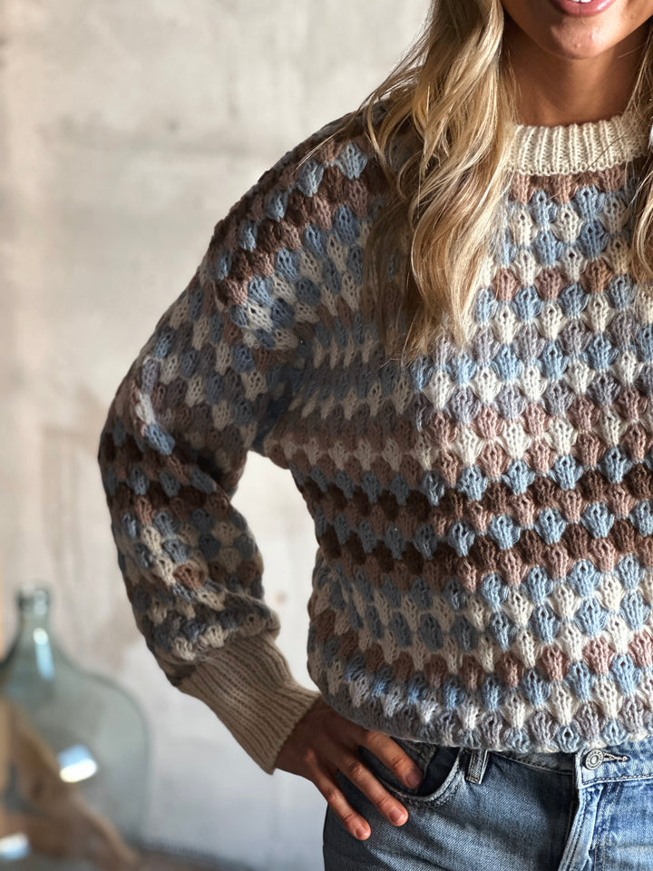 Person wearing a patterned sweater with a neutral background