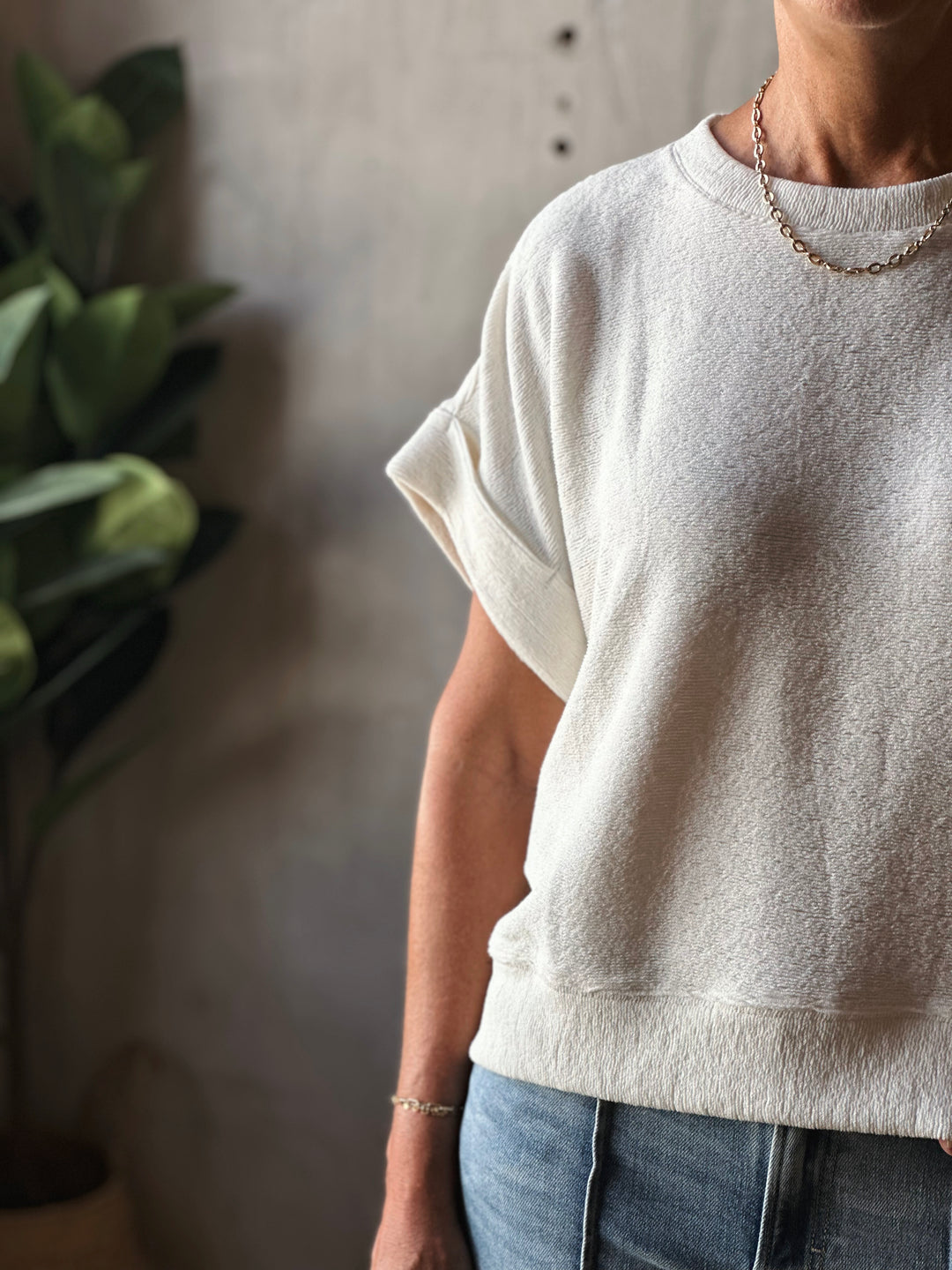 Person wearing a beige t-shirt and blue jeans with a blurred background