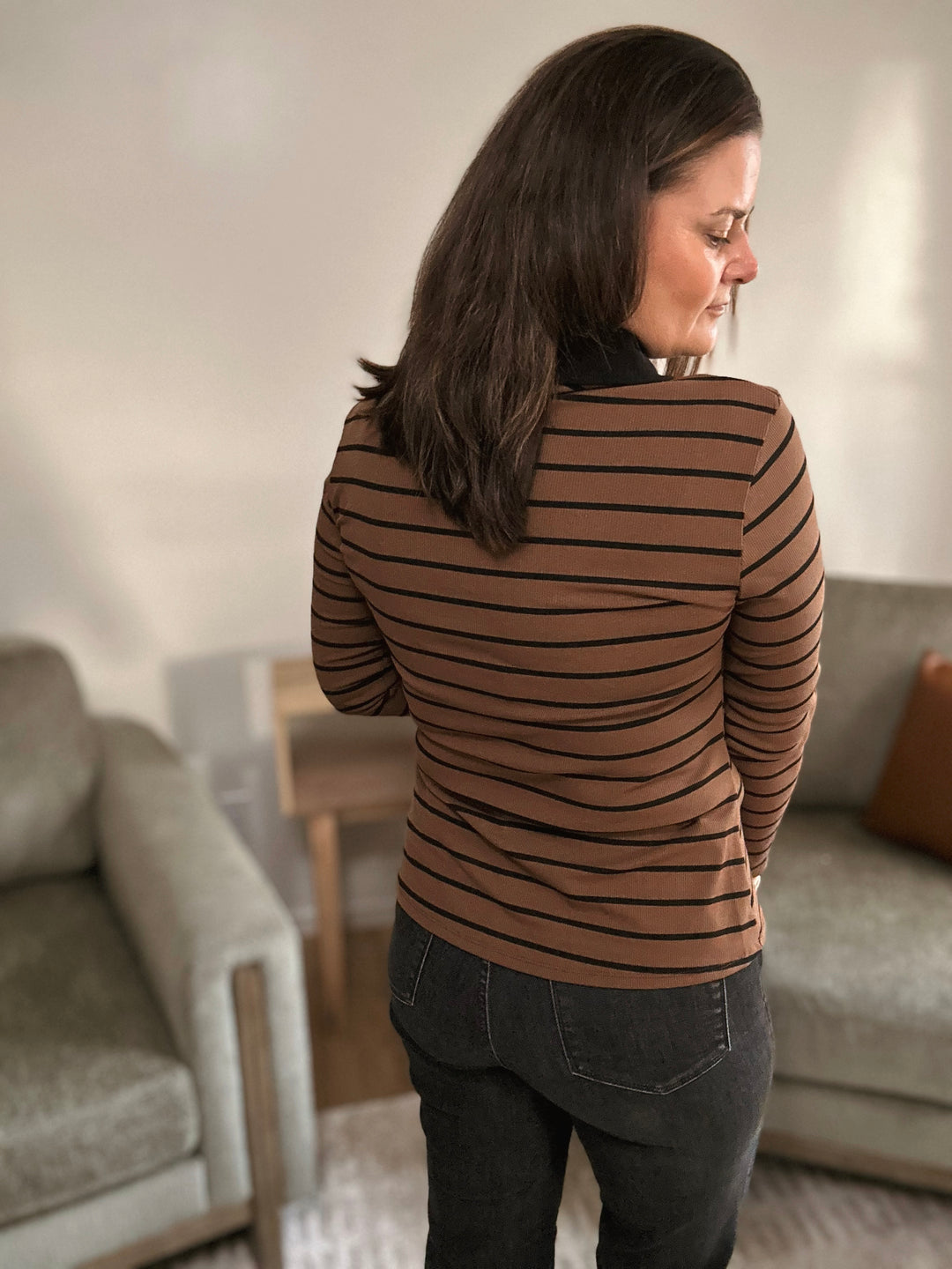 Woman wearing a brown striped sweater in a living room setting