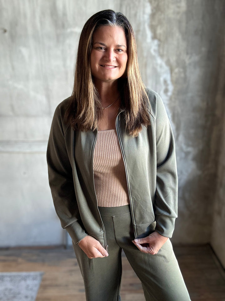 Woman wearing an olive green zip-up sweatshirt with matching pants