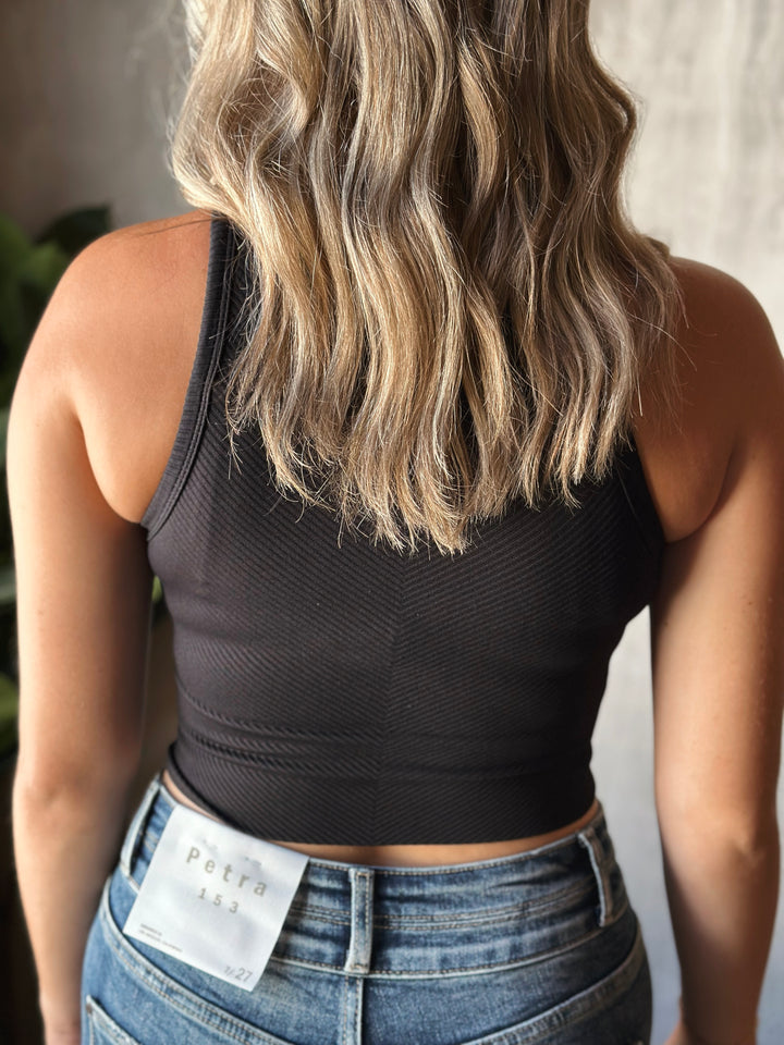 Person wearing a black crop top and blue jeans with a visible brand tag.