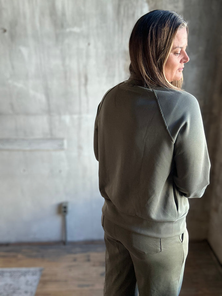 Back view of an olive green zip-up sweatshirt with matching pants