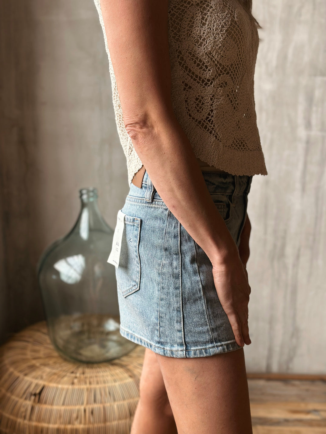 A person wearing light washed denim shorts with a blurred background.