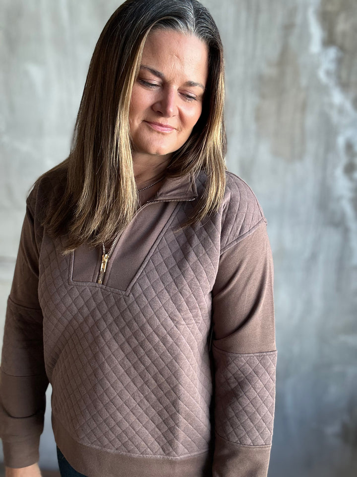 Close-up of a mocha brown quilted half-zip pullover showing the diamond quilting