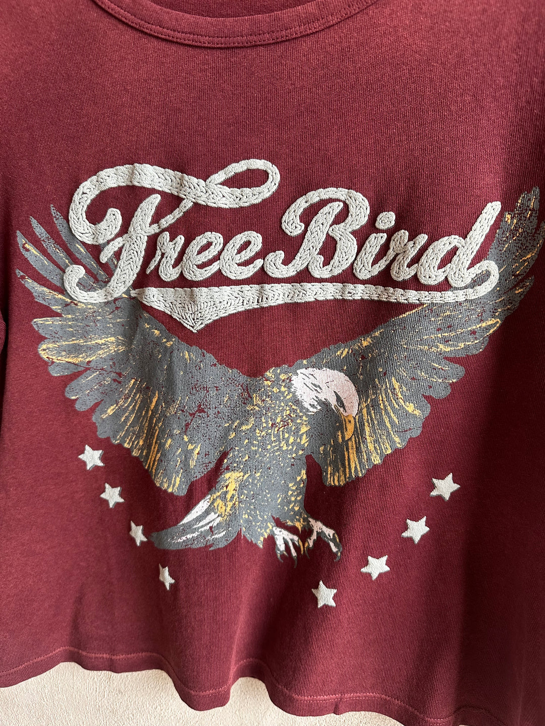 Close-up of the Free Bird eagle graphic on a burgundy tee