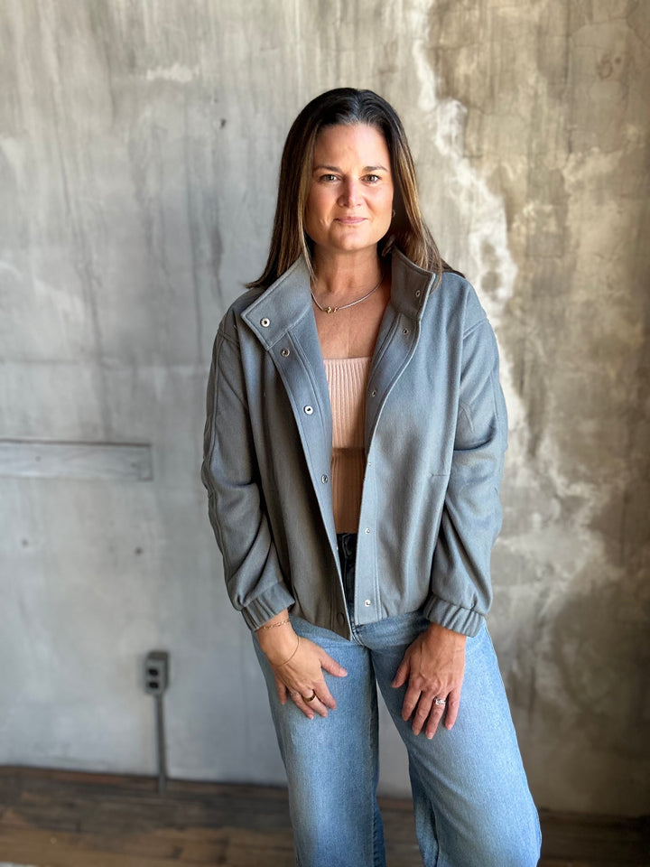 Woman wearing an open slate blue jacket with light-wash jeans, full view