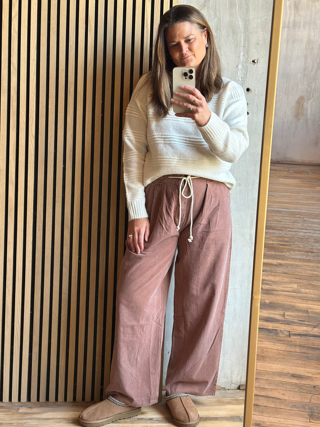 Woman taking a mirror selfie in dusty rose wide-leg drawstring pants and a cream sweater