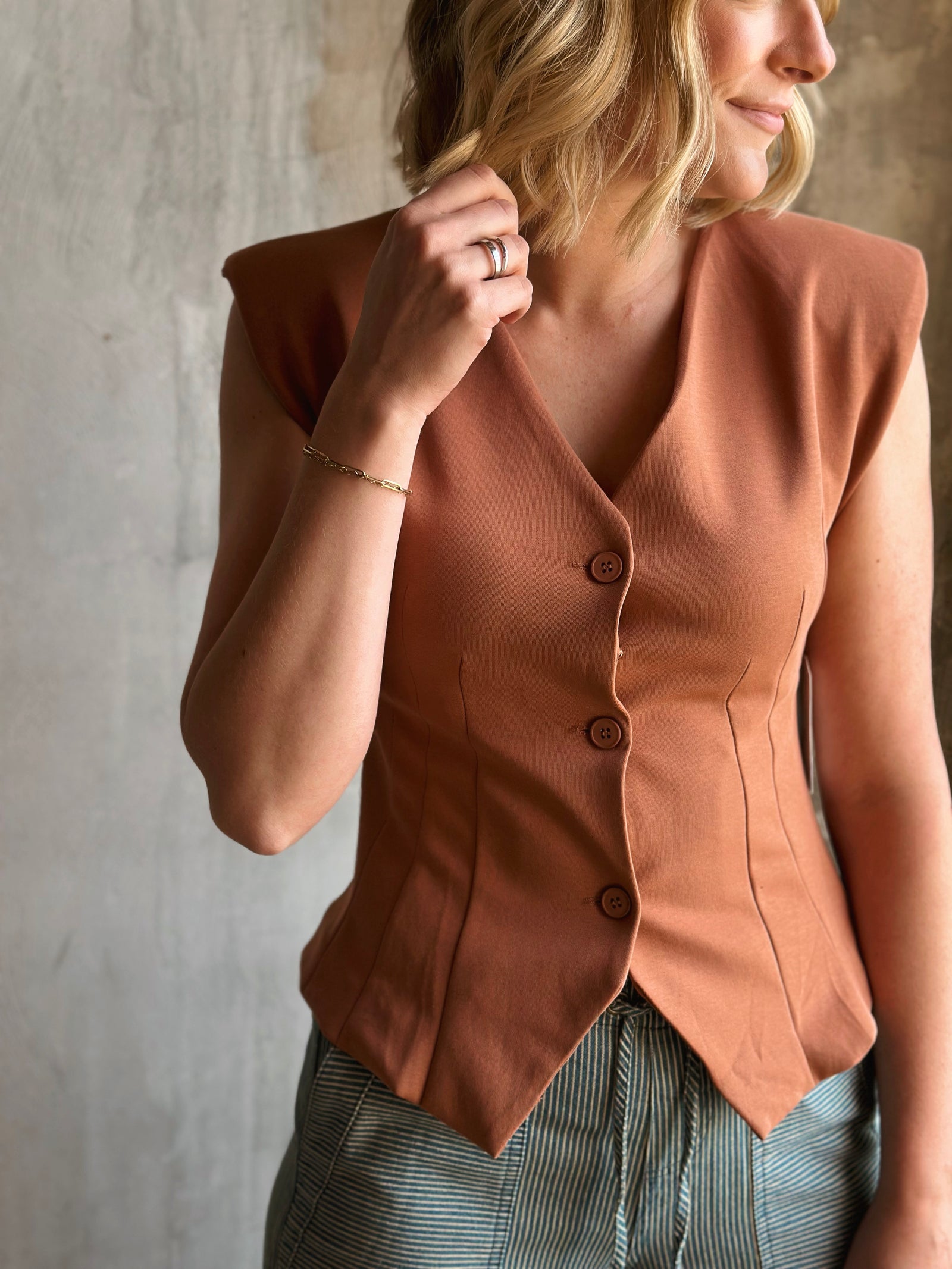 Woman wearing a brown vest against a neutral background